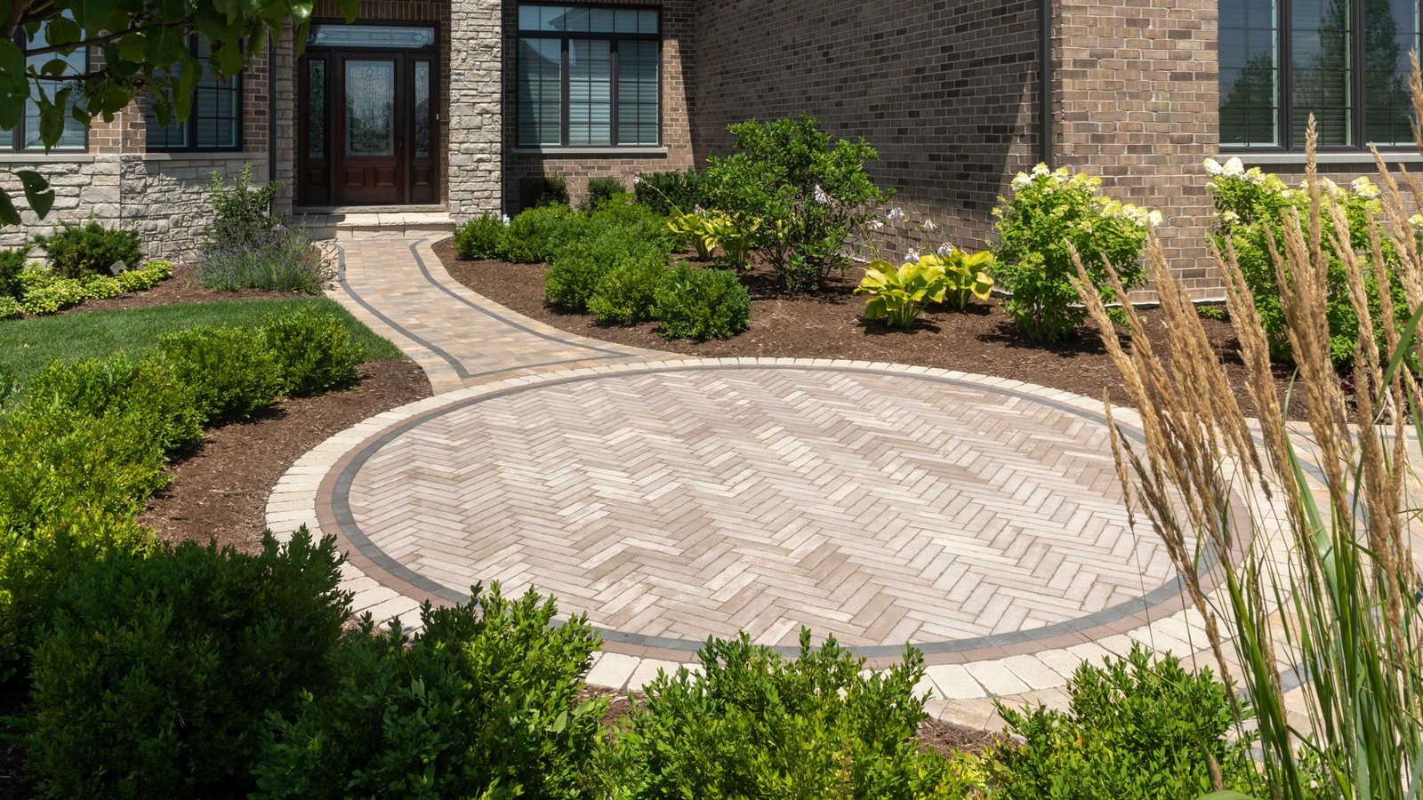 Defined edging borders curved walkway and vibrant shrubs, enhancing symmetry and beauty of front landscape.