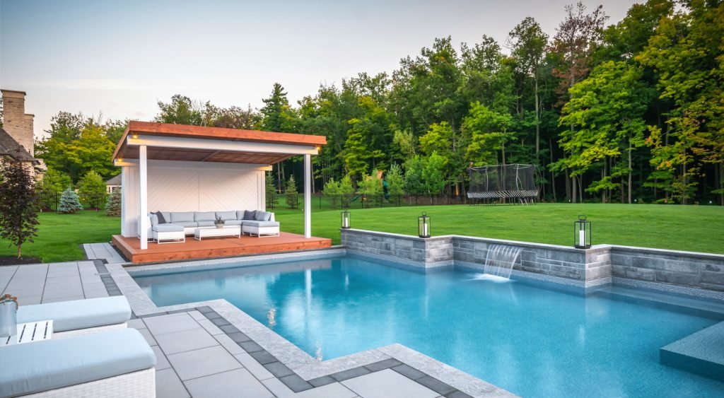 Inviting gazebos with soft cushions and a wooden platform offer a shaded escape next to a modern pool.