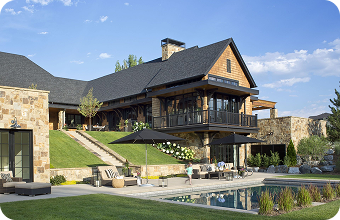 Superior tiered patios with plush seating and umbrellas, enhancing a premium estate's outdoor ambiance against stone.