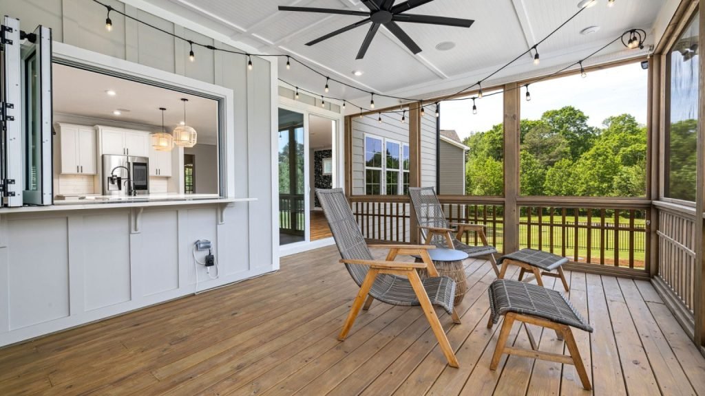 Stylish covered deck with wood flooring, ceiling fan, and comfortable lounge chairs.