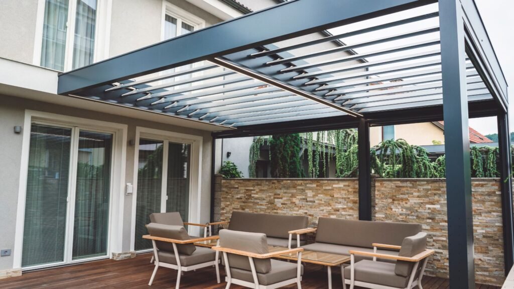 Pergola with minimalist design adds elegance and shade to patio with cushioned seating and privacy wall.